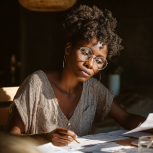 a black woman sitting at a table taking notes about micro schools