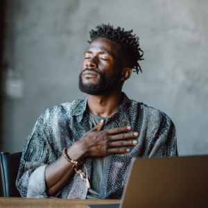black man with short locs with his eyes closed with his hand over his heart. taking a breathe thinking about his child's report card